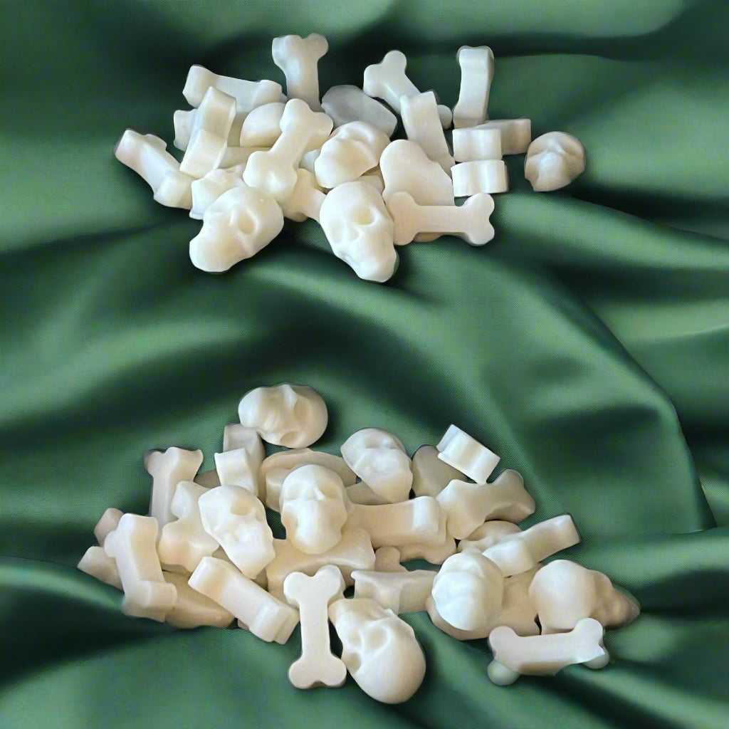 White skull and bones wax melts arranged on a green textured surface.