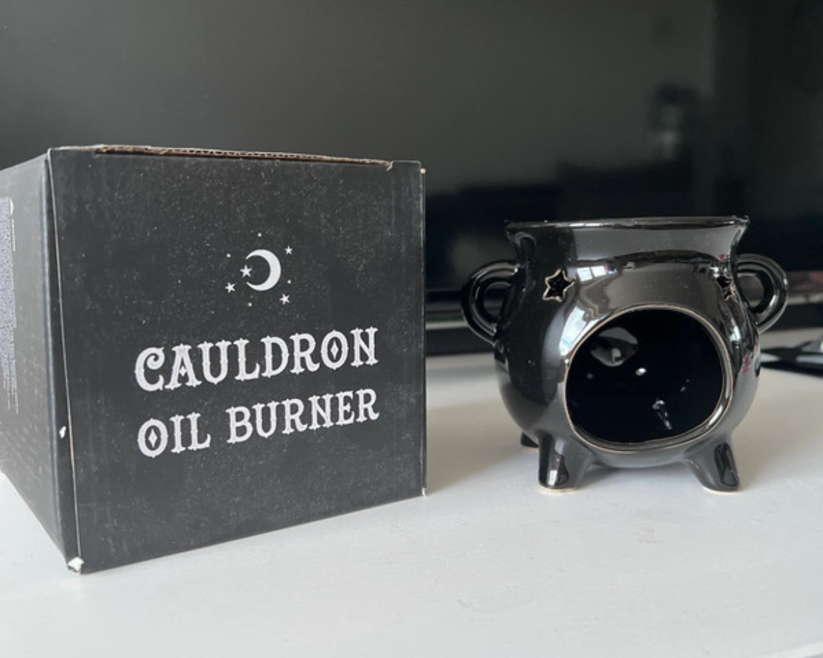 Black oil burner with packaging labeled 'Cauldron Oil Burner' on a white surface.