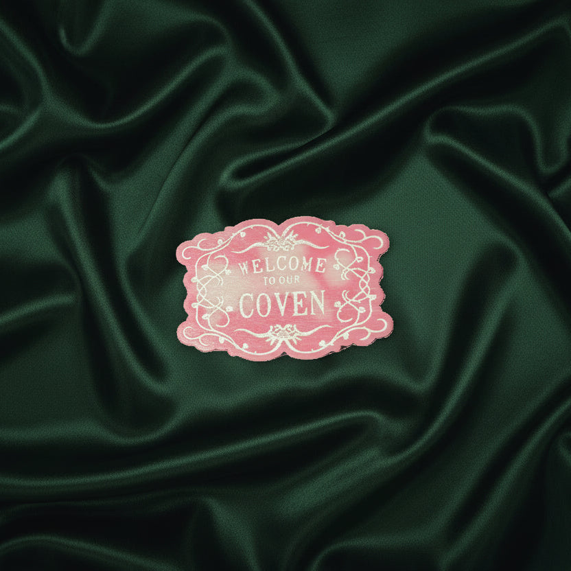 welcome to the coven wax melt on a green fabric background