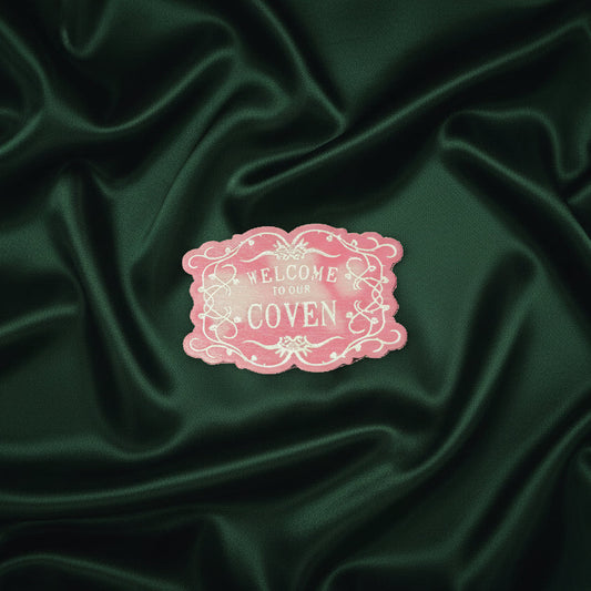 welcome to the coven wax melt on a green fabric background