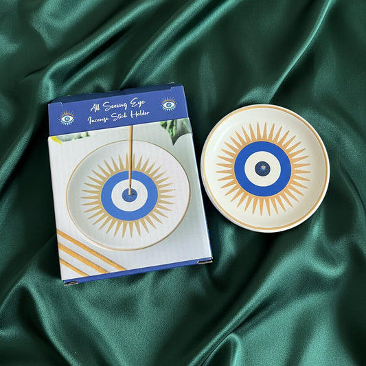 Decorative plate with a blue and gold design on a matching box, both on green fabric.