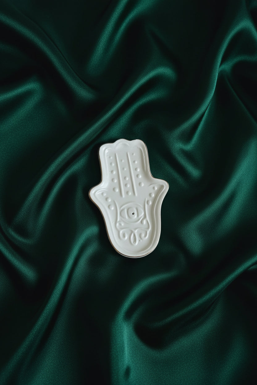 White ceramic Hamsa hand on green fabric