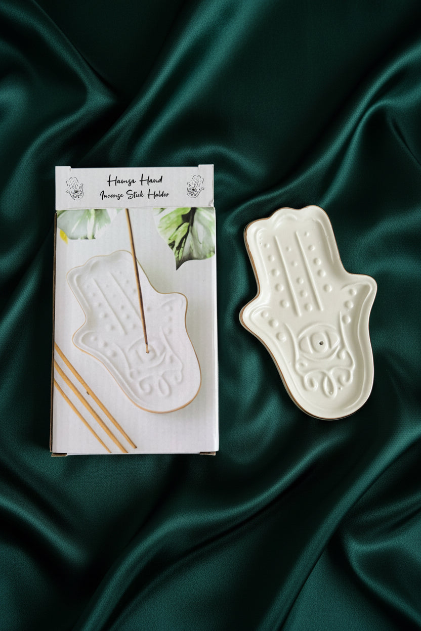 White ceramic hamsa-shaped tray on a green fabric background