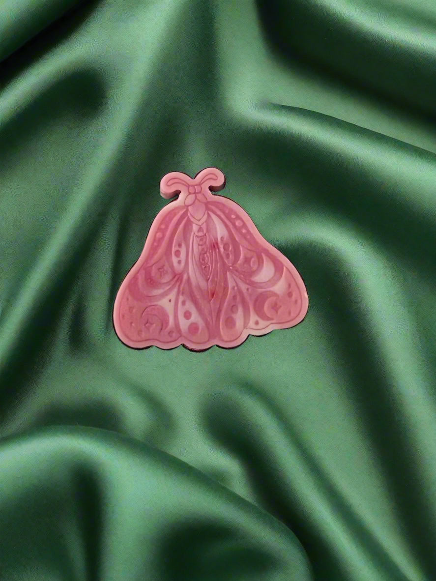 A Luna Moth wax melt with intricate patterns, placed on a green textured surface.
